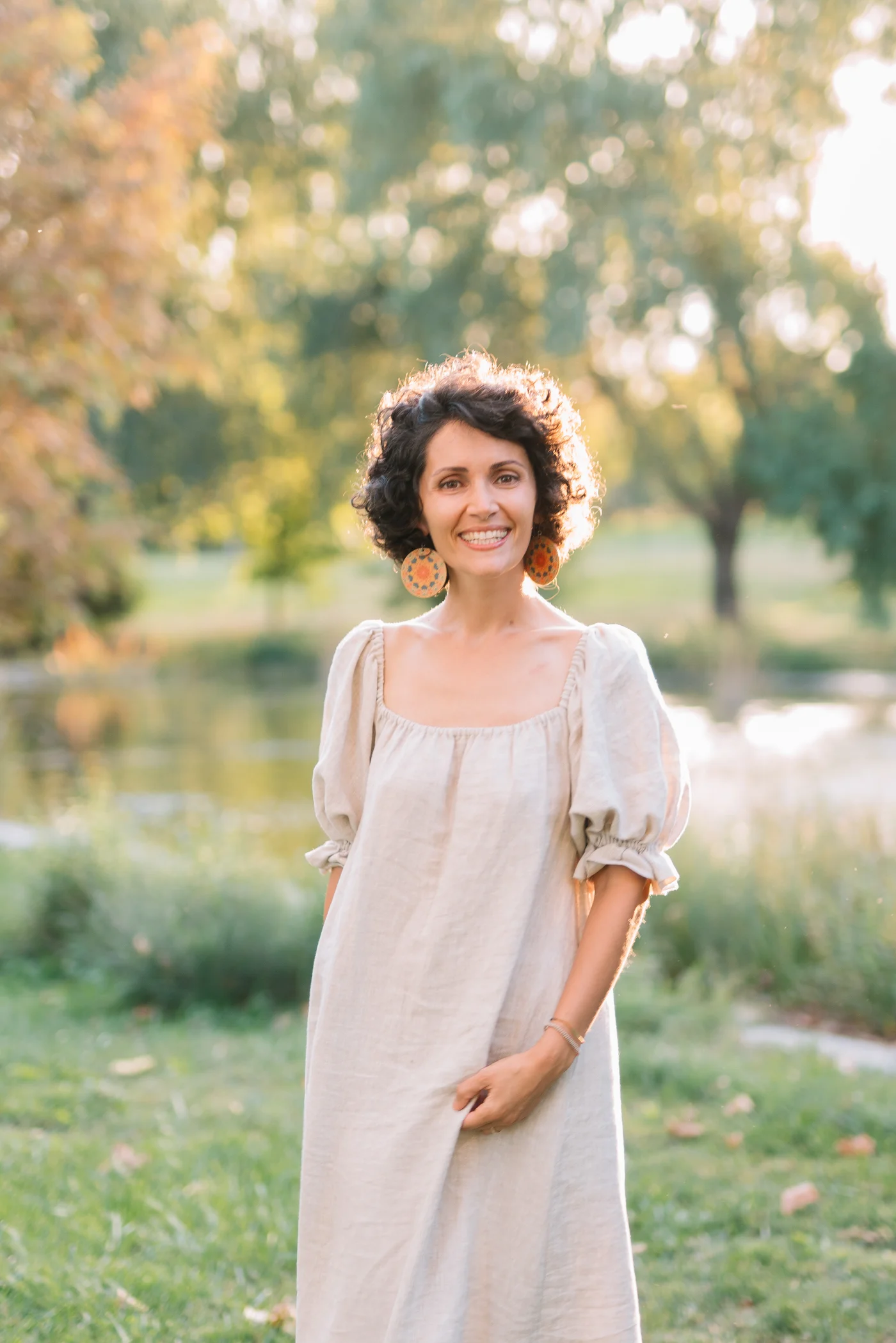 Alexandra zâmbește către cameră, într-o grădină în lumină caldă.
